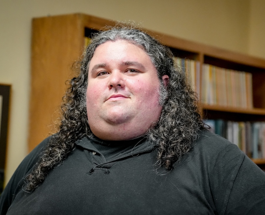 man standing in front of bookshelf looking at camera