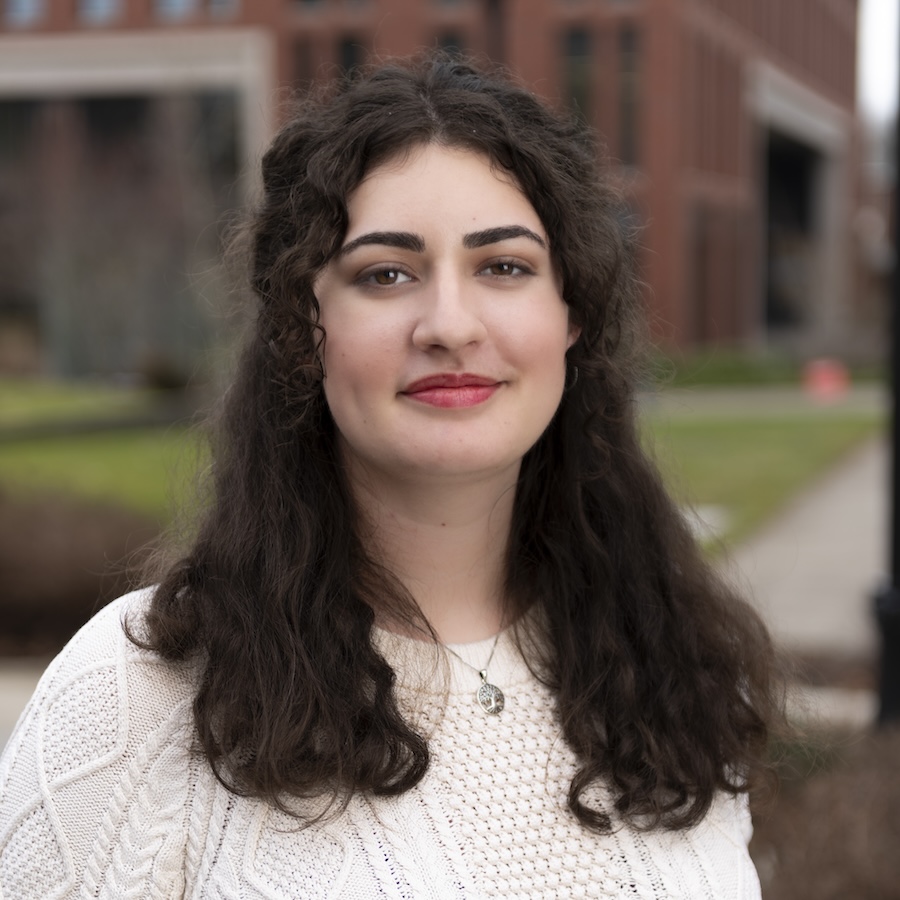 a woman wearing a white sweater standing in front of a building