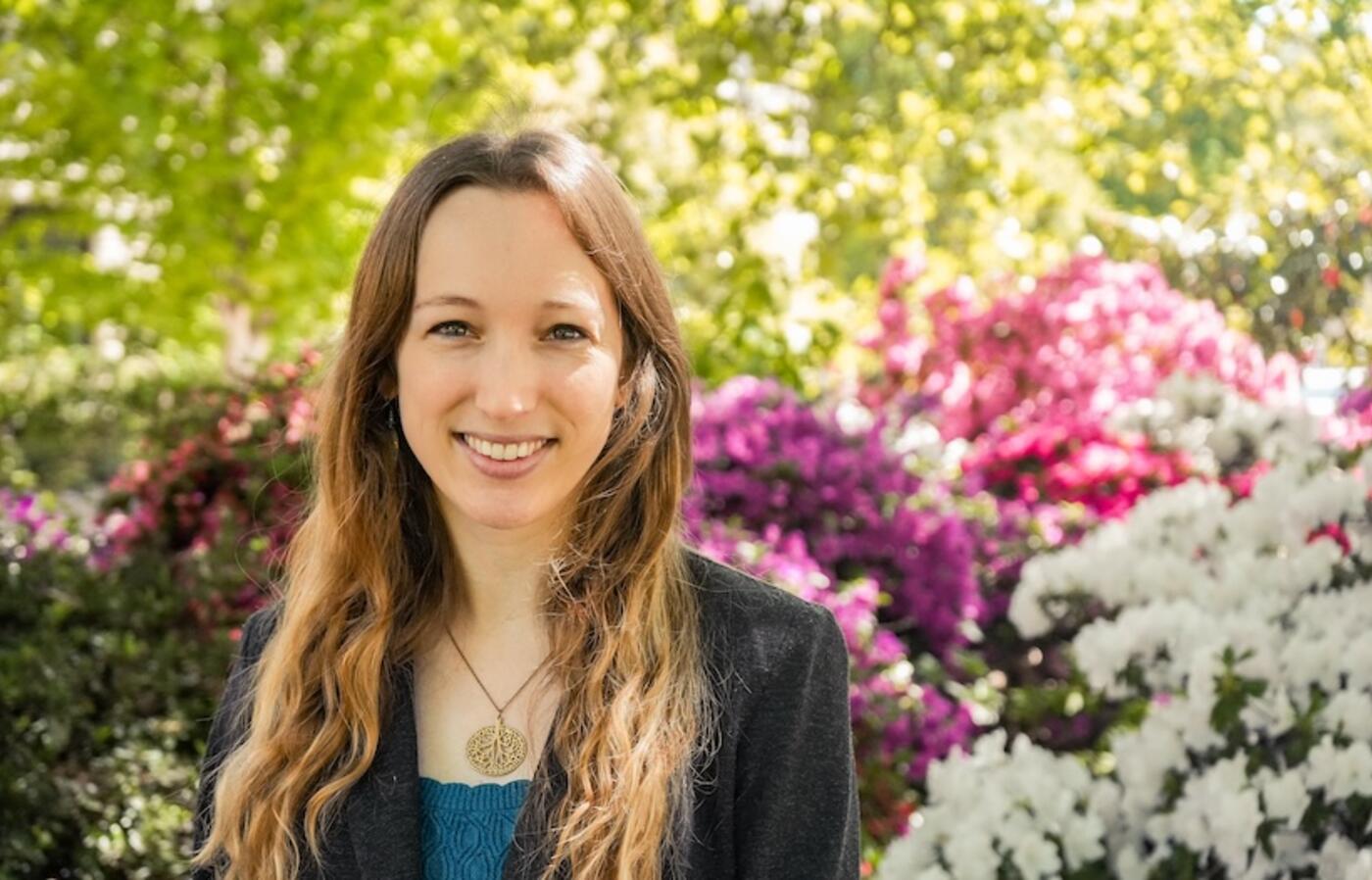 woman standing in front of flowering bush smiling at camera