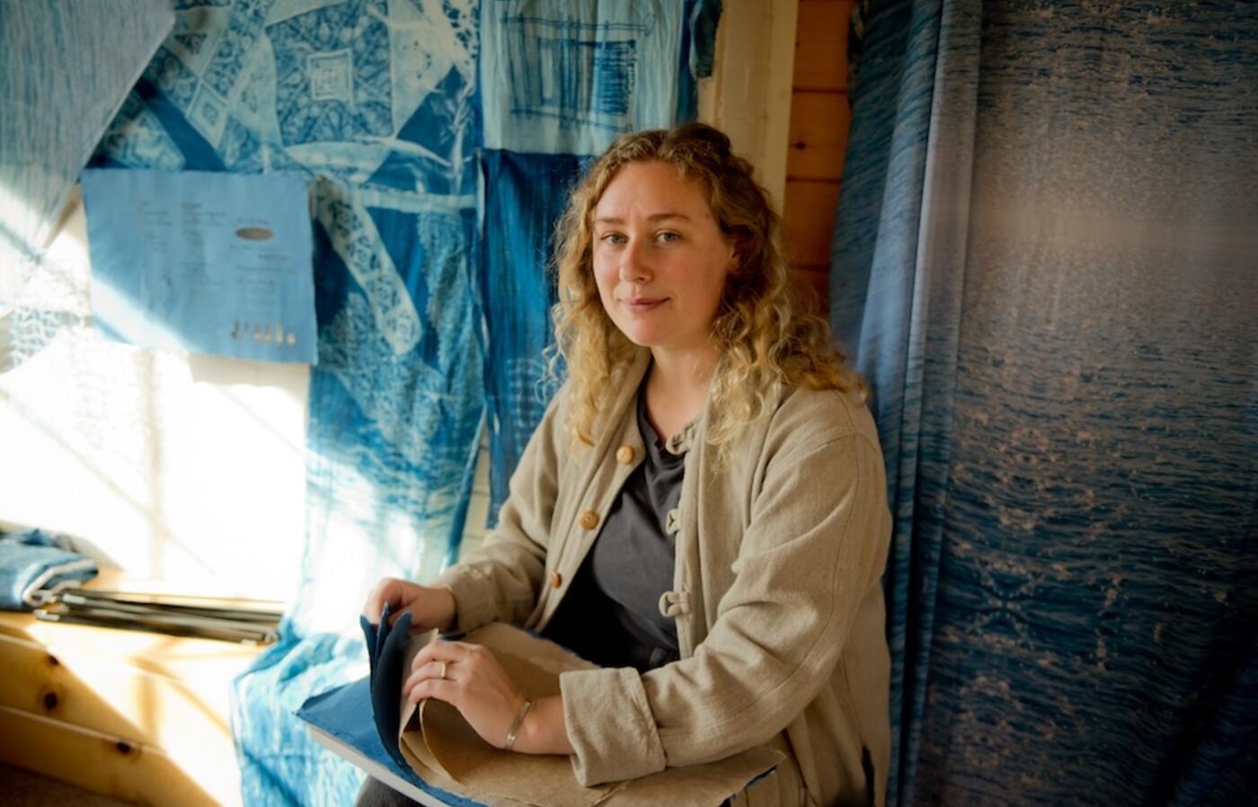 a woman sitting in front of her woven art