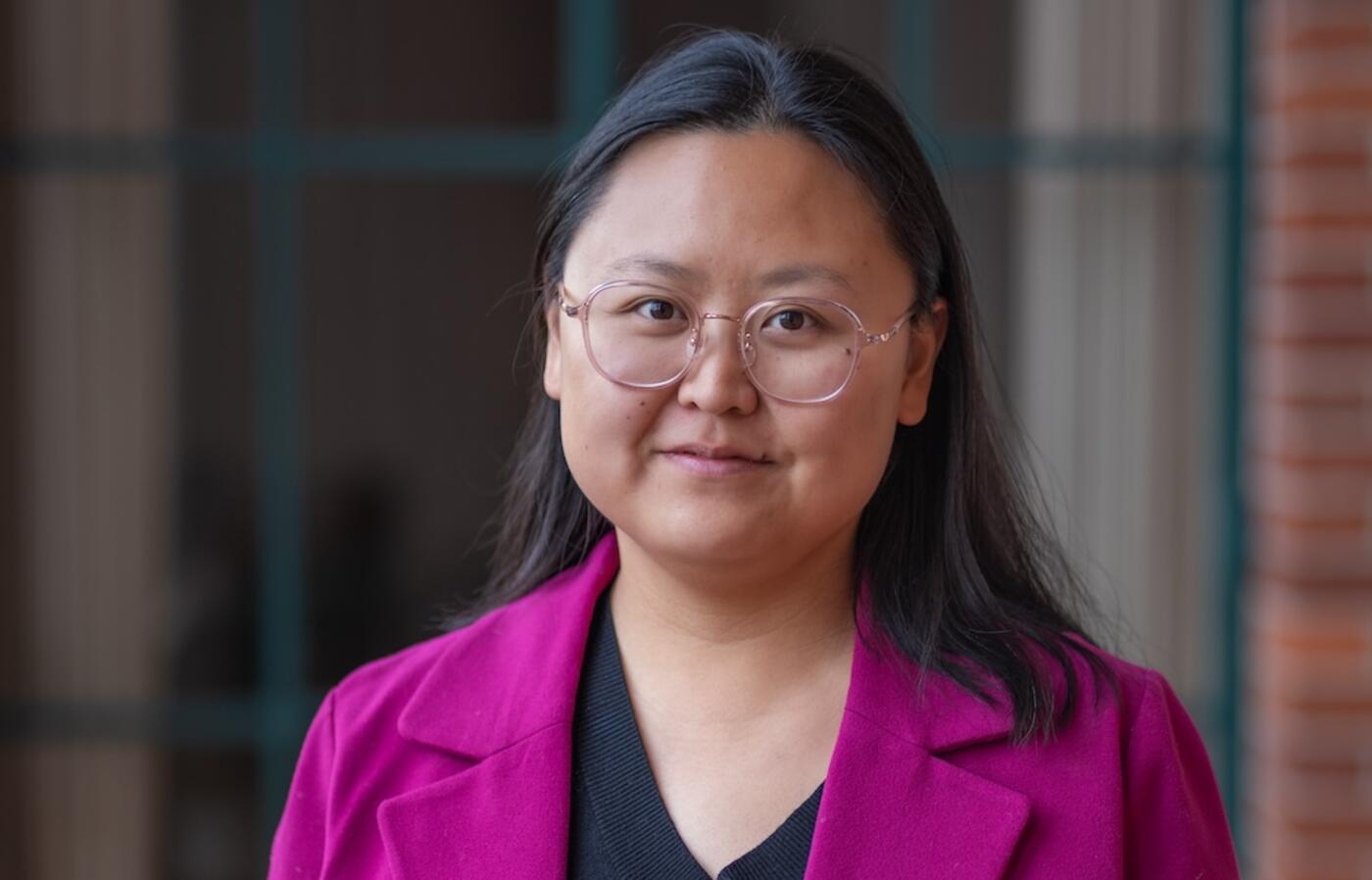 a woman in a purple vest and black shirt looking at the camera