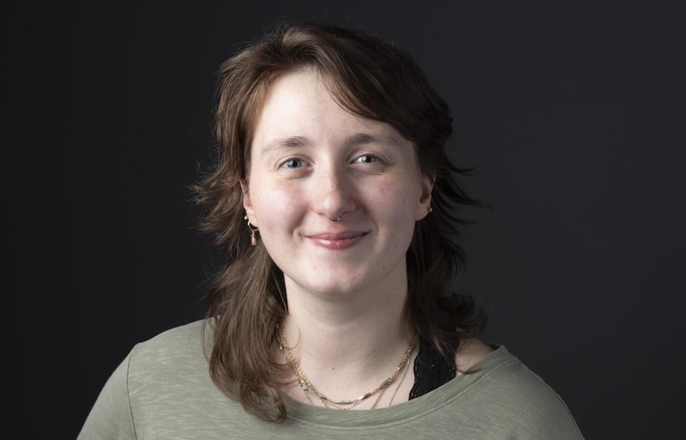 person wearing a green sweater smiling at the camera