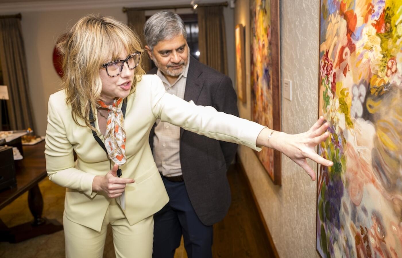 two people looking at a painting hanging on the wall