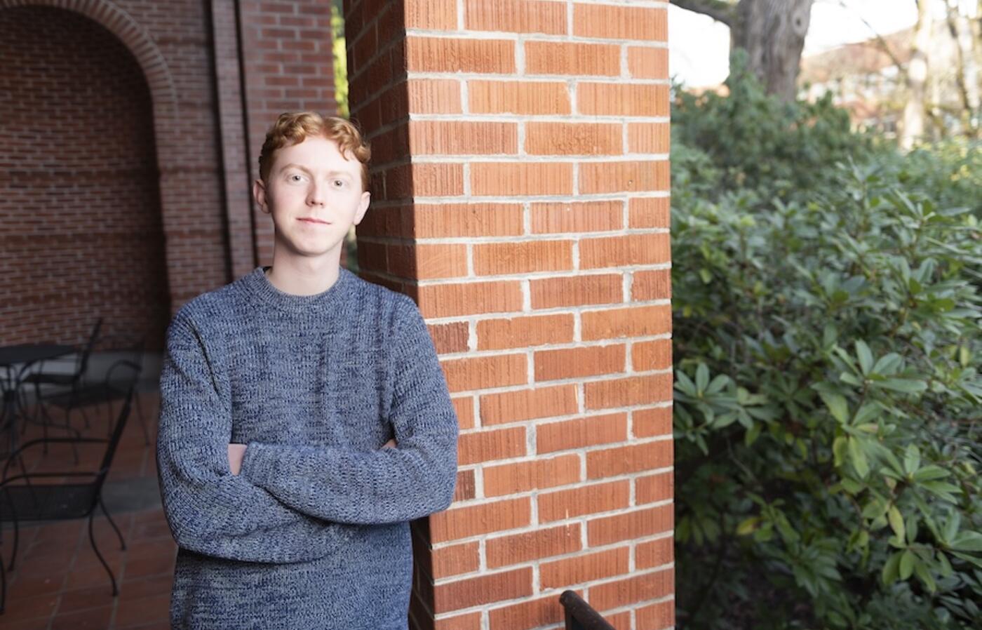 Colby Beck standing in front of a brick column