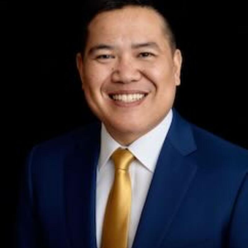 headshot of Bernie Wang.  He is wearing a blue suit and gold tie.  
