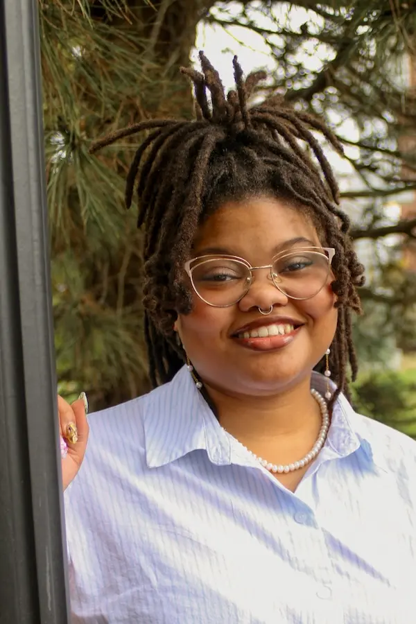 person in blue shirt and glasses smiling at camera