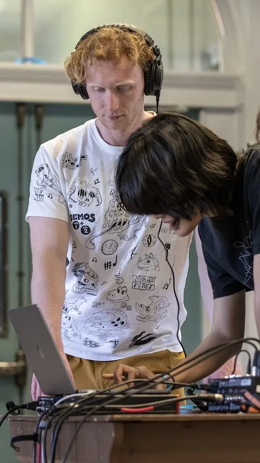 two people looking at a computer with their headphones on