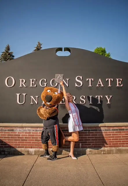 Benny the Beaver with Hailey standing in front of a sign that says Oregon State University