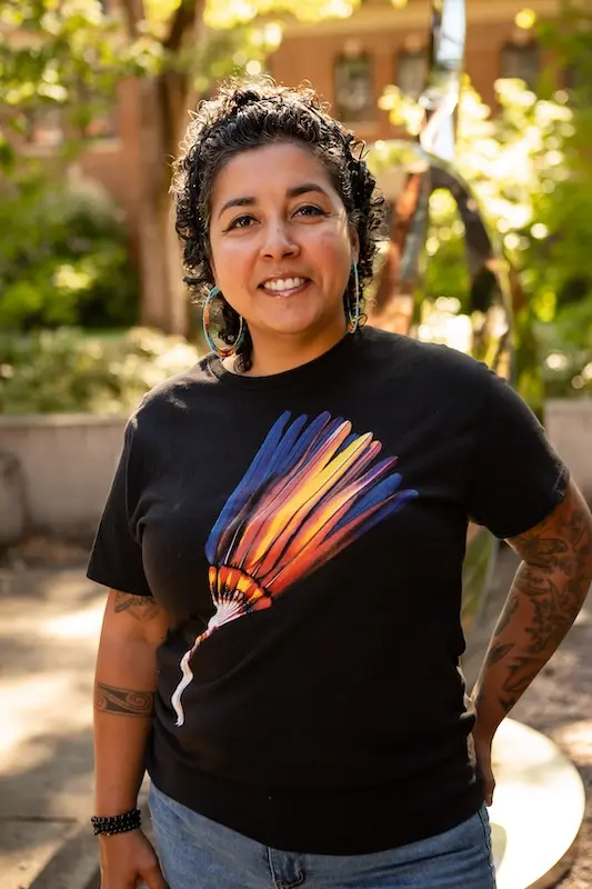 woman in a black shirt and jeans smiling at the camera