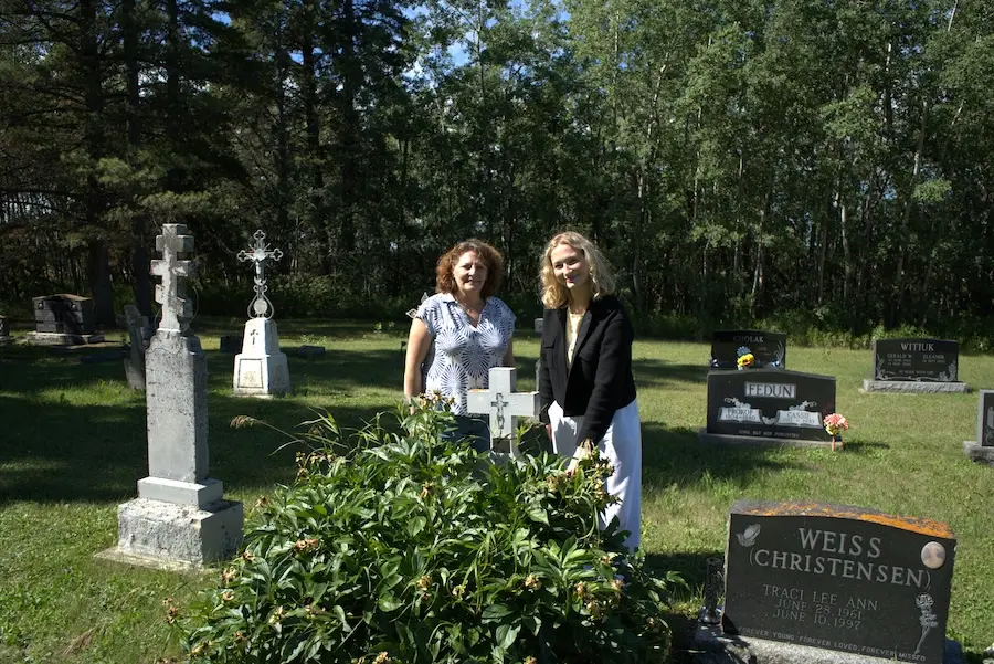 two women standing over a gravesite