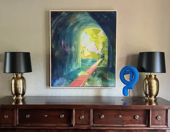 a hanging painting with a sculpture on a dresser