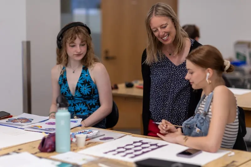 art teacher working with students in a design studio