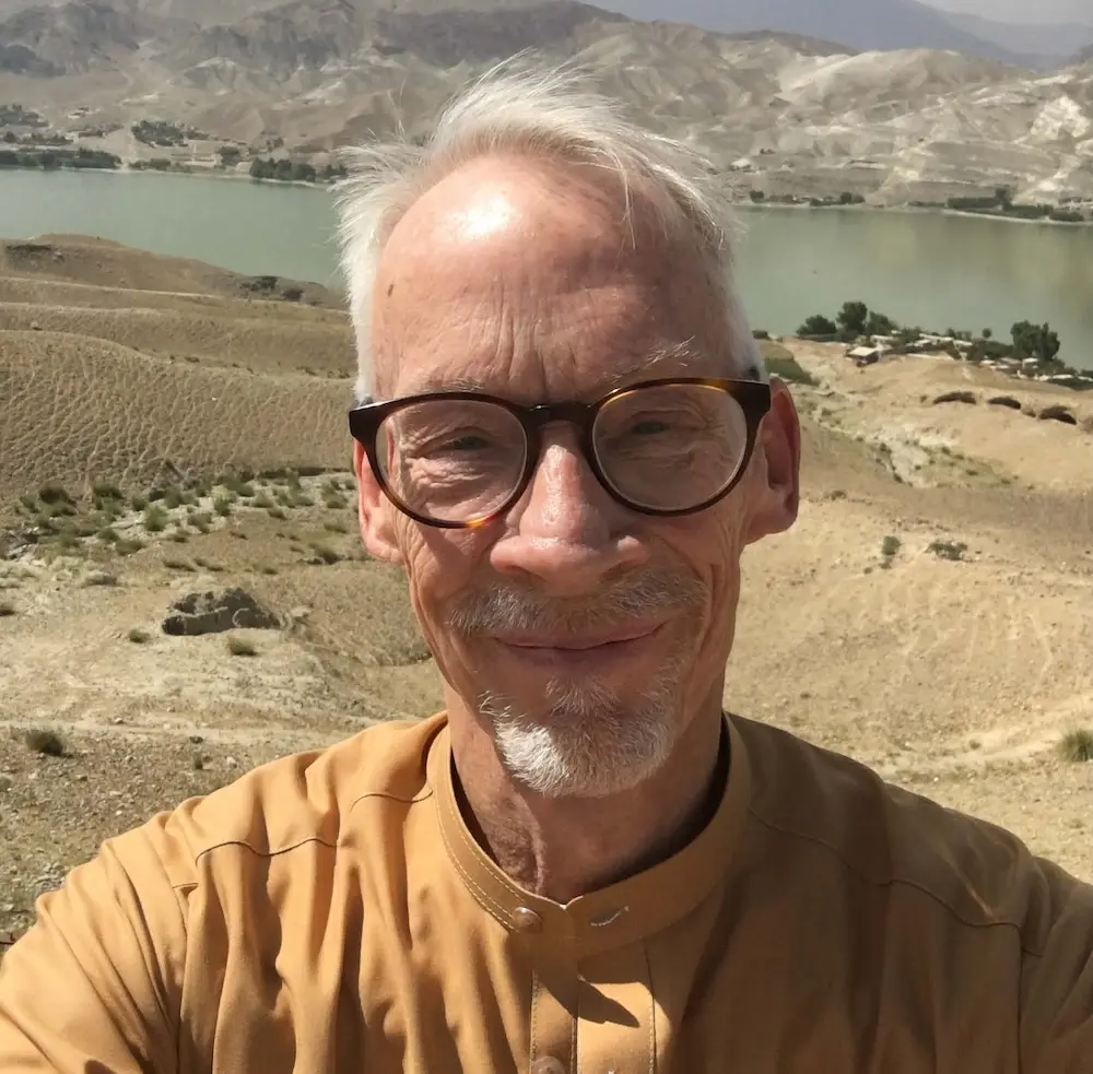 a self of a man wearing glasses standing on a cliff