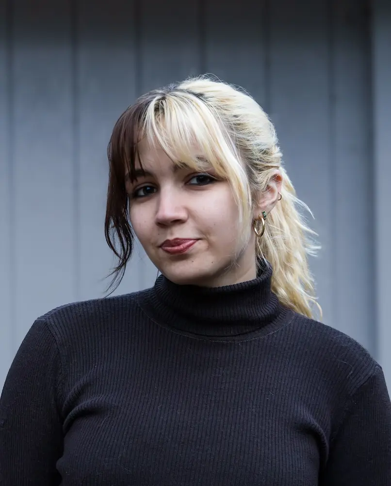 person wearing a black sweater standing in front of a grey background