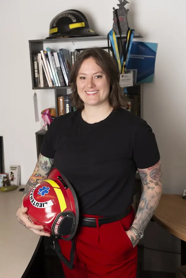 woman standing in an office holding a fire fighter's helmet