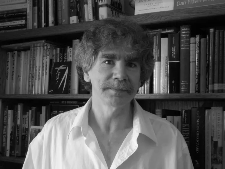 a black and white picture of a man standing in front of a bookcase