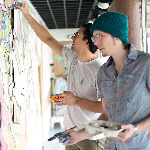 2 students painting on a wall